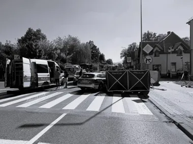 Policyjne i ratunkowe pojazdy zabezpieczają skrzyżowanie w miejscowości, gdzie ustawiono parawan na przejściu dla pieszych.